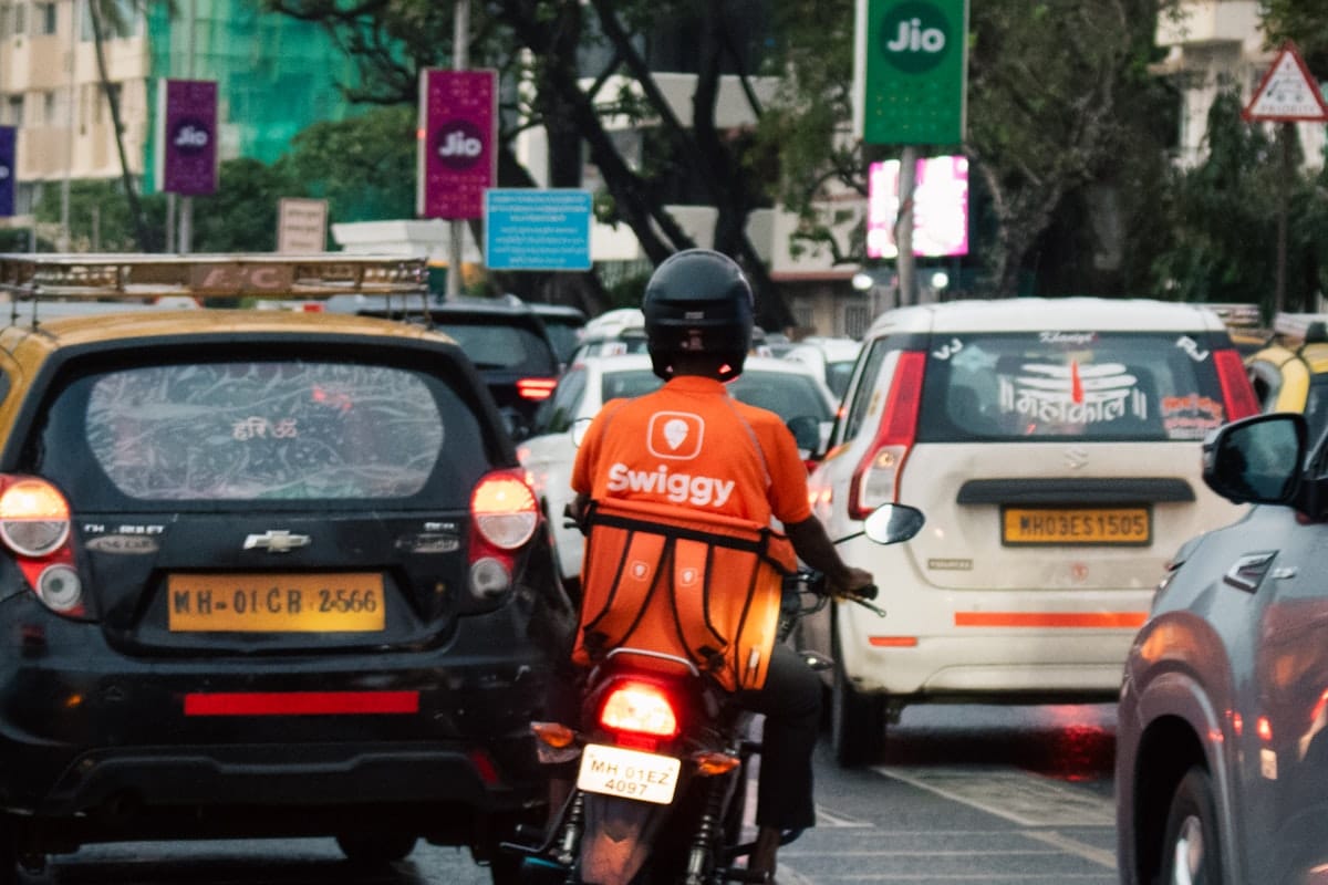 A delivery rider on a motorcycle in Mumbai traffic